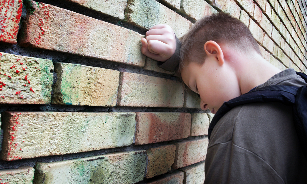 despondent child head against wall